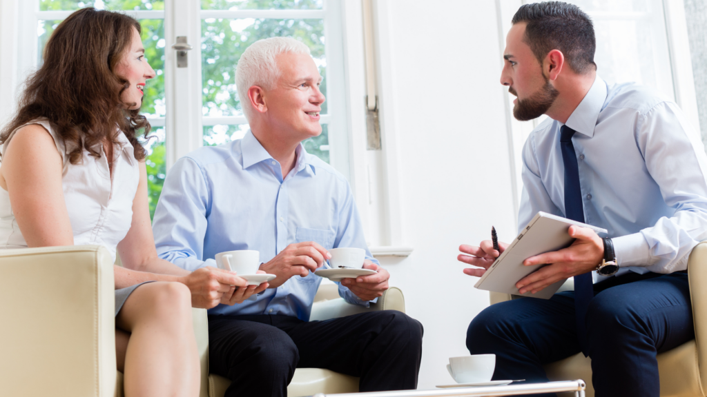 Man and women drinking out of tea cups talking to a man