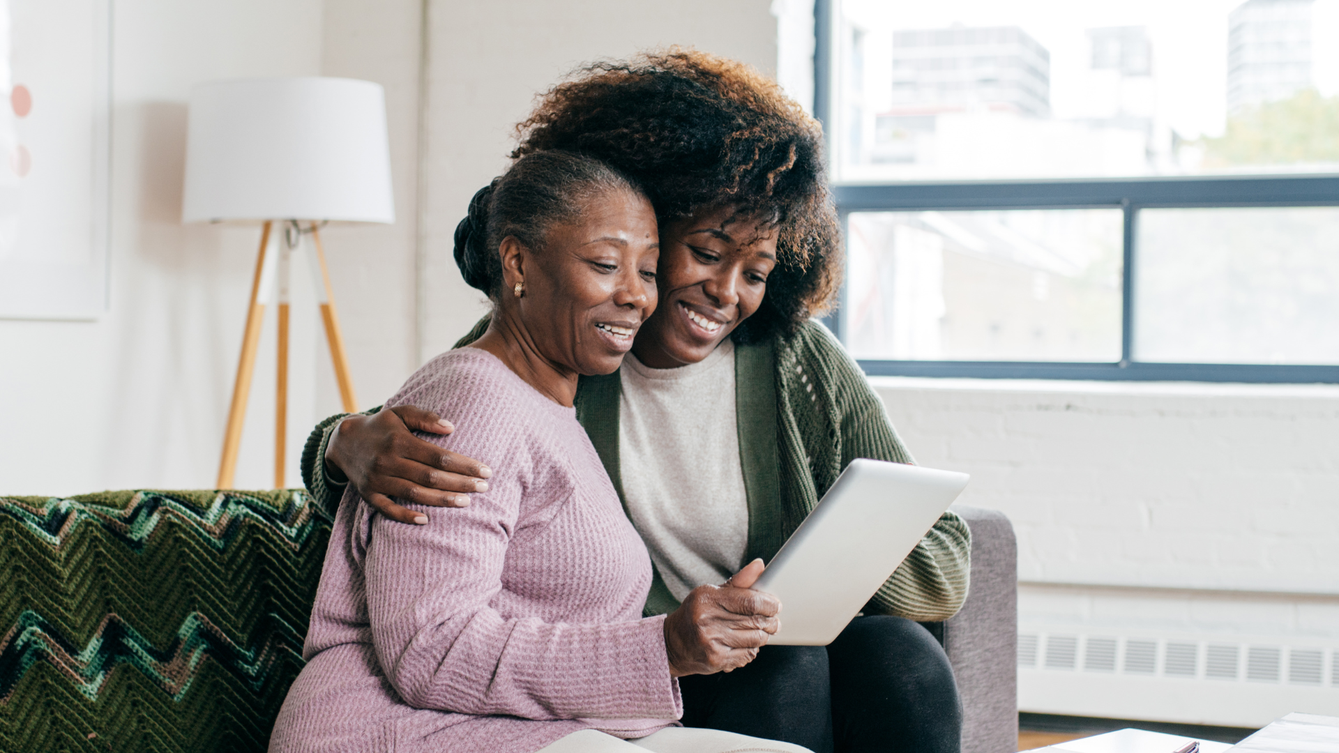 Women hugging and smiling at Ipad